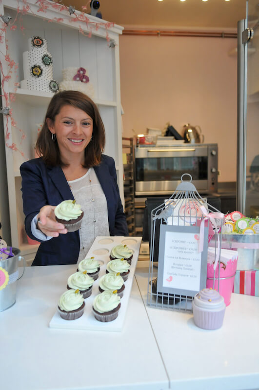 Bertie holding one of her speciality cupcakes in her cupcakery in Paris