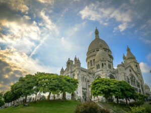Sacré-Cœur Basilica just before sunset with people sitting on grass in square Louise Michel